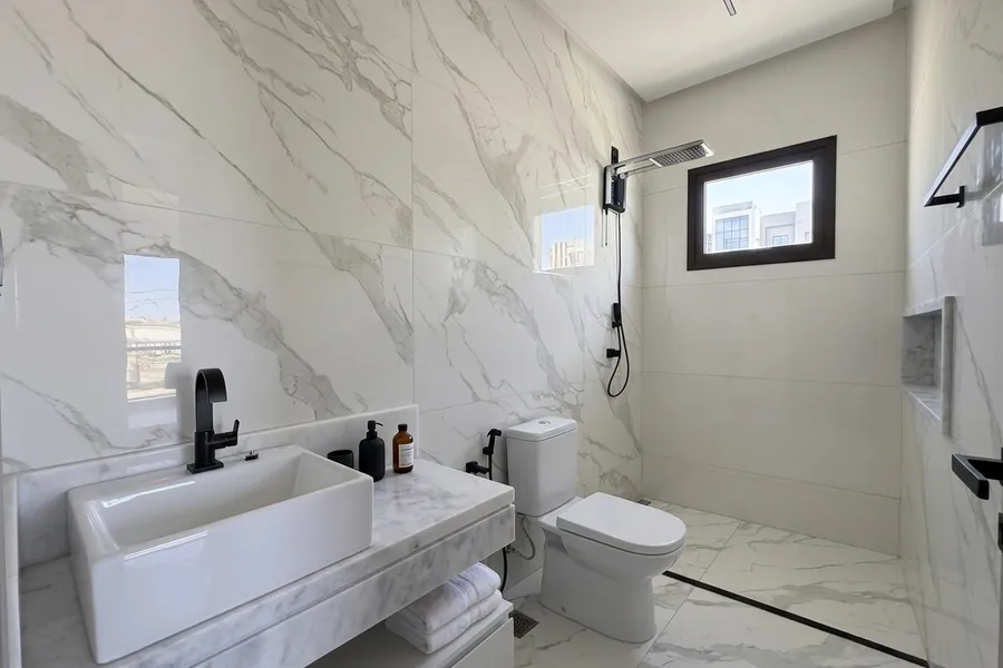 Banheiro da suíte do Lar MH&D, revestido em mármore branco