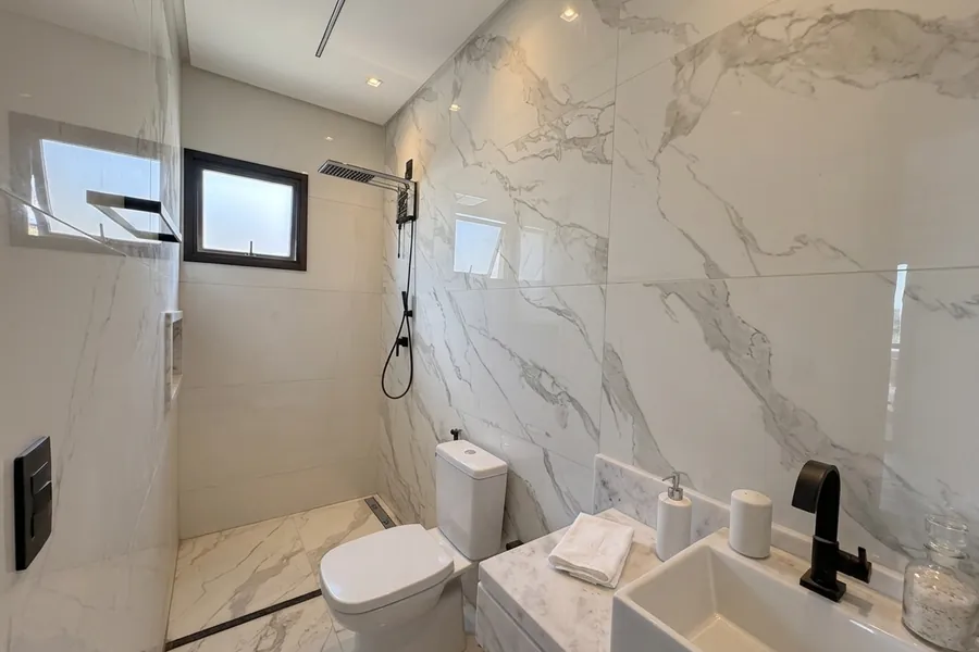 Banheiro do Lar MH&D com bancada em mármore e metais pretos